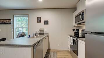 A modern kitchen with a central island, stainless steel appliances, and a view to the outdoors.