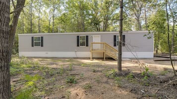 A mobile home with a wooden deck and a staircase leading to a covered porch.