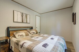 Un dormitorio con cama, mesita de noche, puerta y un cuadro colgado en la pared.
