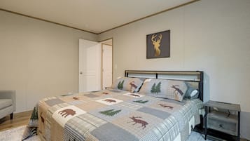 A bedroom with a bed, a nightstand, a door, and a wall-mounted deer head decoration.