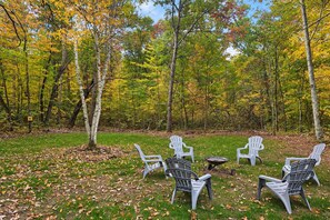 A forest with chairs and a fire pit.