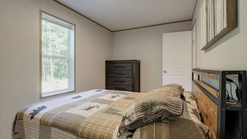 A bedroom with a bed, a dresser, a door, and a window.