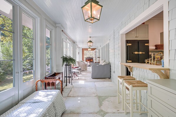 A long hallway with a bench, a dining area, and a kitchen with wooden cabinets.