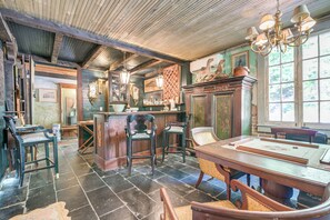 A room with a wooden ceiling, a bar area, and a dining table with chairs.
