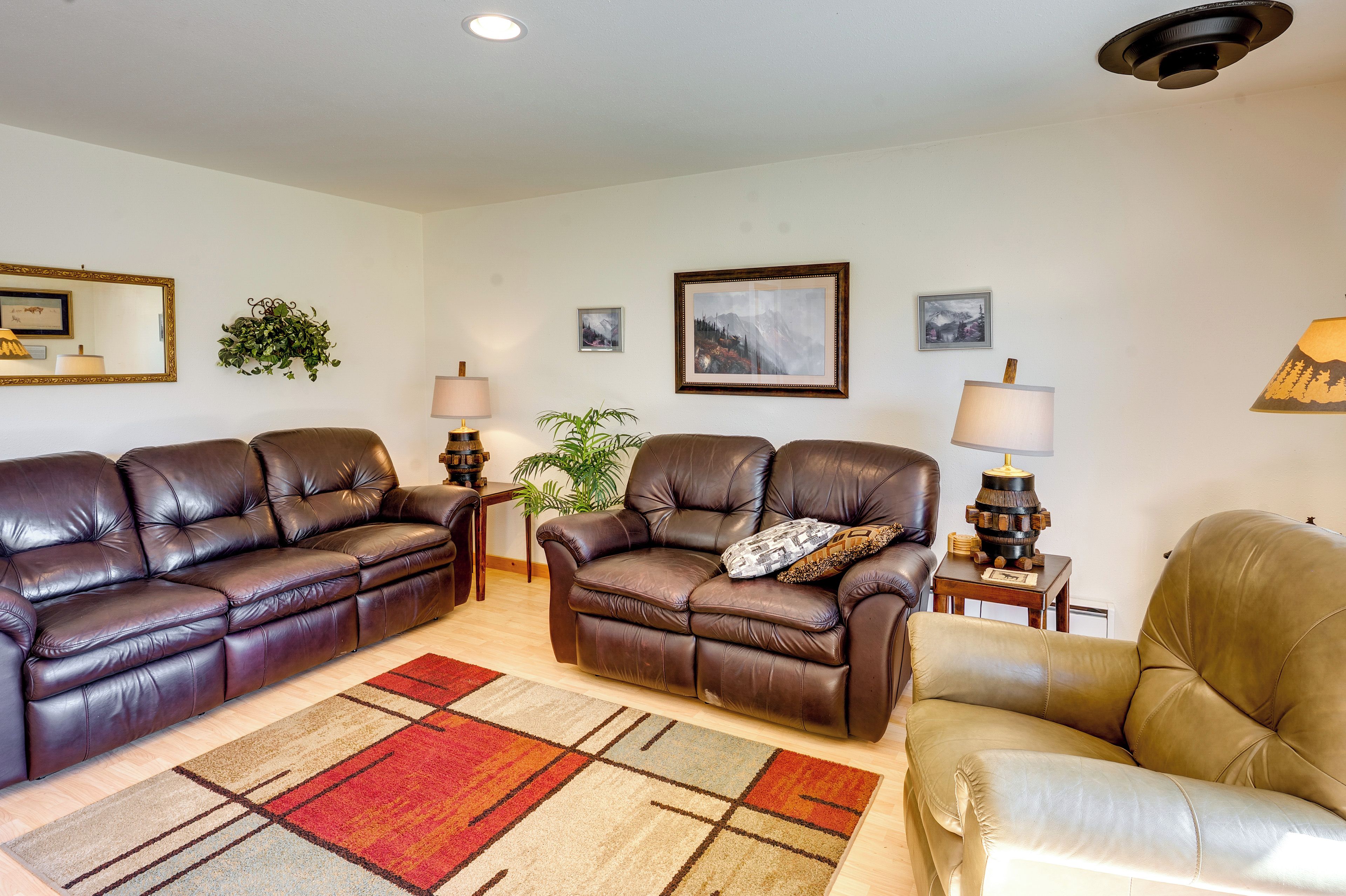 A living room with two leather sofas, a coffee table, a patterned rug, and wall-mounted lamps.