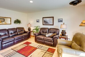 A living room with two leather sofas, a coffee table, a patterned rug, and wall-mounted lamps. - Walk to Yellowstone River! Emigrant Home w/ Patio (Emigrant)