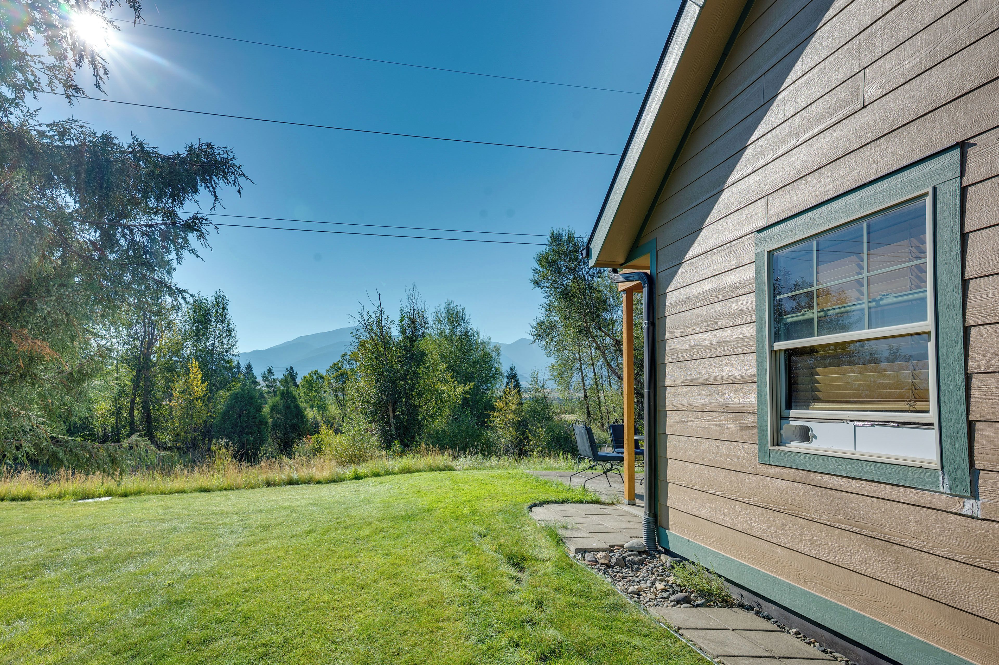 A house with a wooden exterior, a clear sky, and a mountain in the background.
