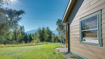 A house with a wooden exterior, a clear sky, and a mountain in the background.