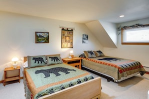 A bedroom with two beds, each with a bear-themed quilt, a nightstand with a lamp, and a wall with three framed pictures. - Walk to Yellowstone River! Emigrant Home w/ Patio (Emigrant)
