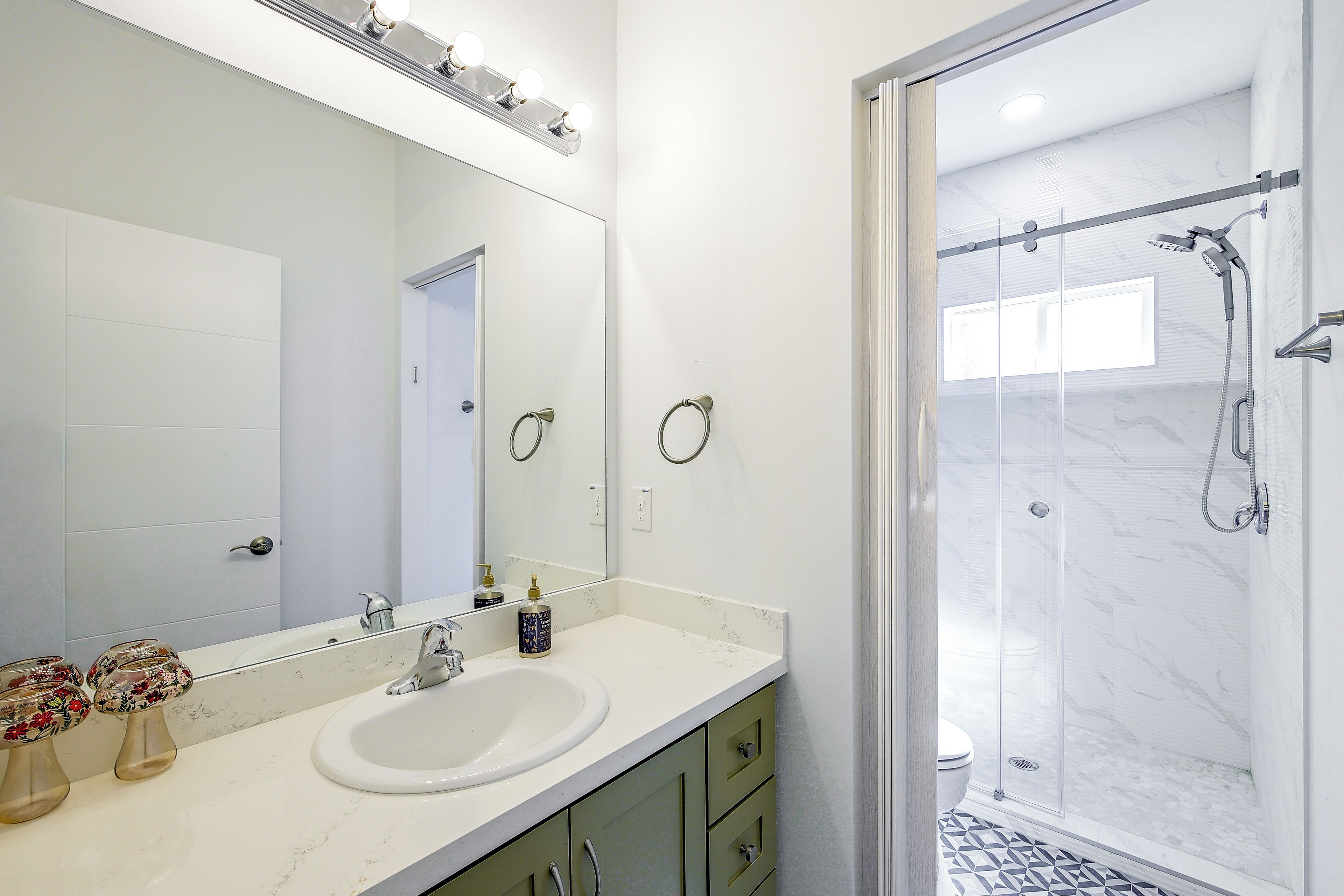 A modern bathroom with a large mirror, a sink, and a shower area.