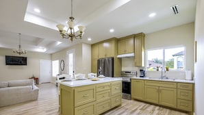Una cocina moderna con una isla central, electrodomésticos integrados y un rincón de comedor con sofá.