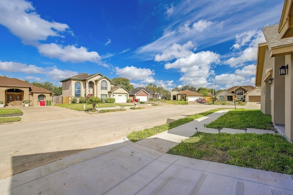 A residential street with houses, a clear sky, and a well-maintained sidewalk. - Single Home: Spacex, Hwy 511 & Beaches (Brownsville)