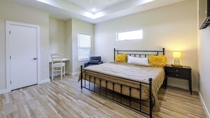 Un dormitorio con cama, una silla, un escritorio, una mesita de noche y un ventilador de techo.