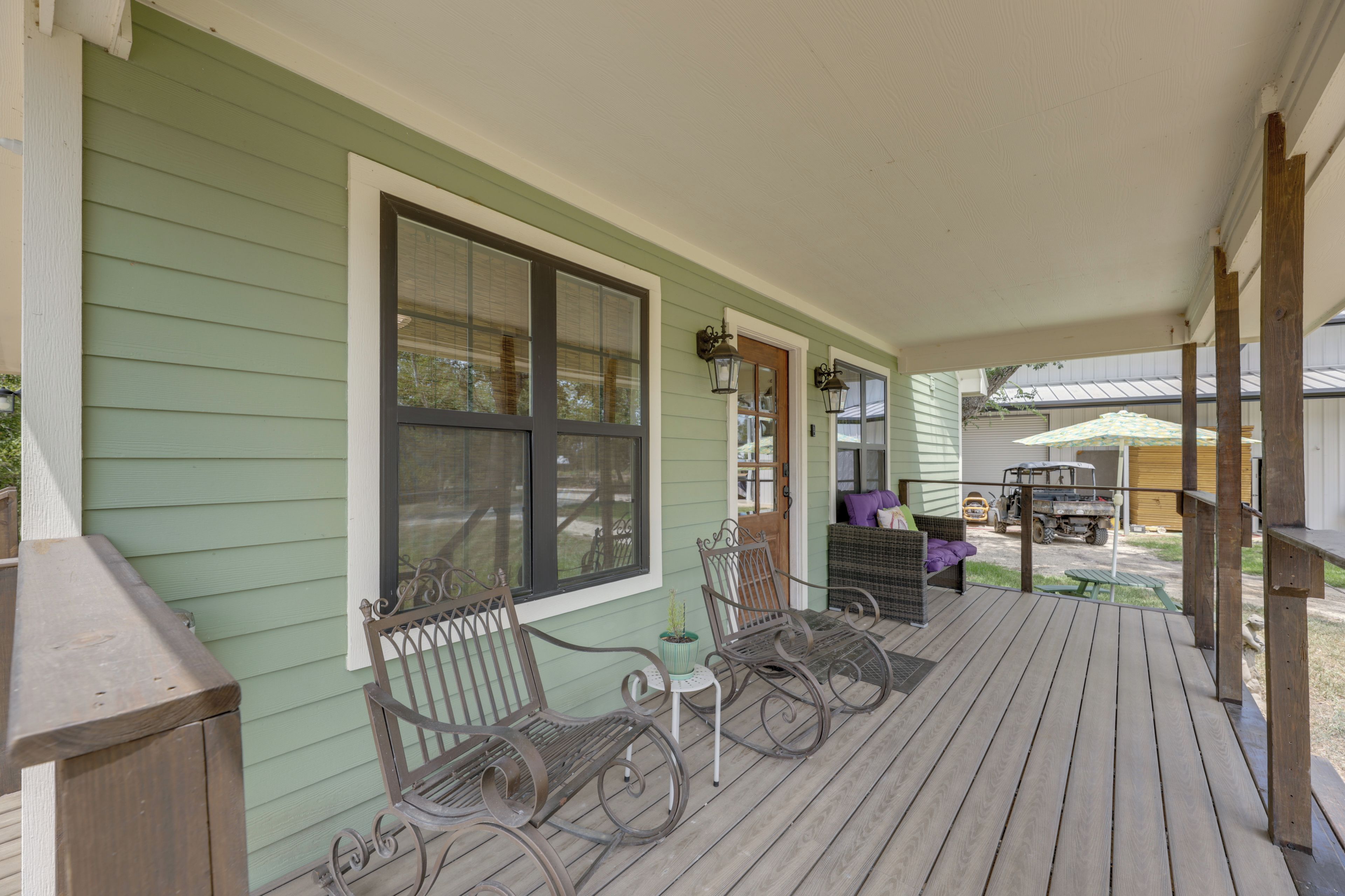 A covered porch with two rocking chairs, a small table, and a bench.
