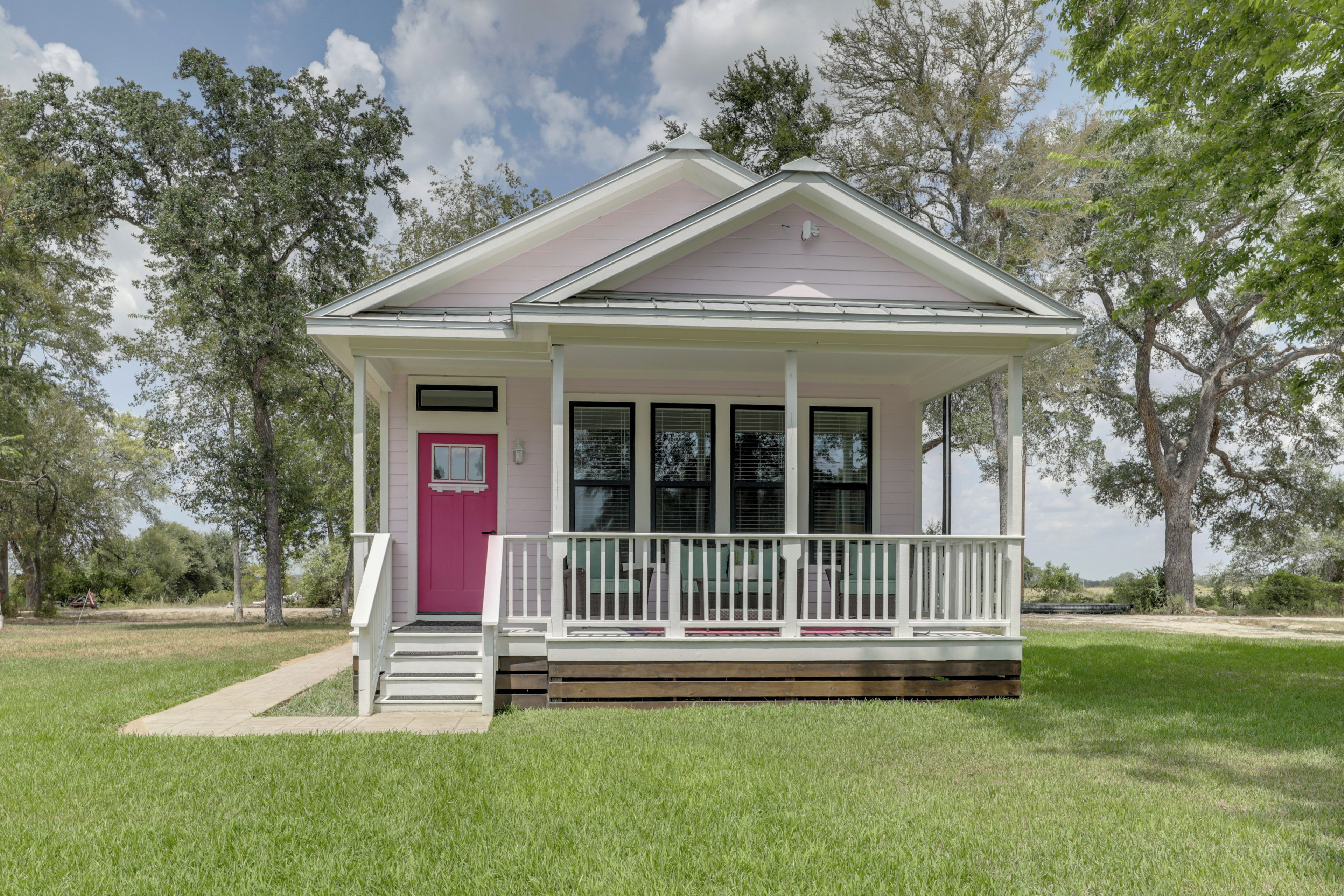 A single-story house with a front porch, a pink door, and a small front yard.