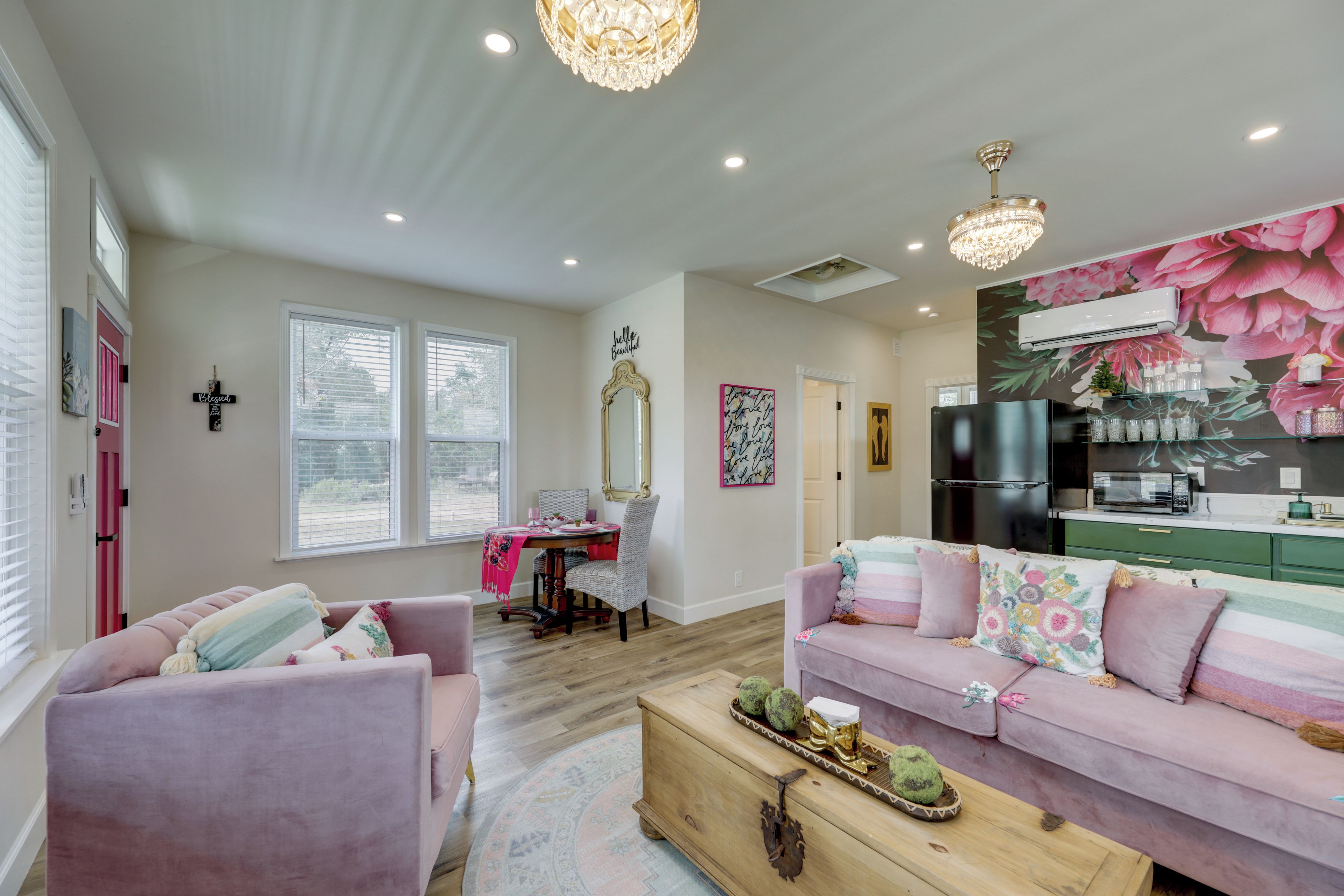 Una sala de estar con un sofá rosa, una mesa de centro de madera y un comedor con una mesa y sillas.