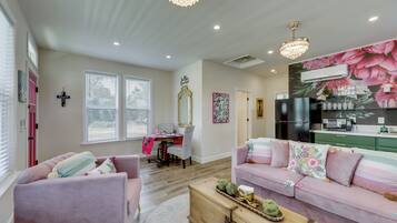 Una sala de estar con un sofá rosa, una mesa de centro de madera y un comedor con una mesa y sillas.