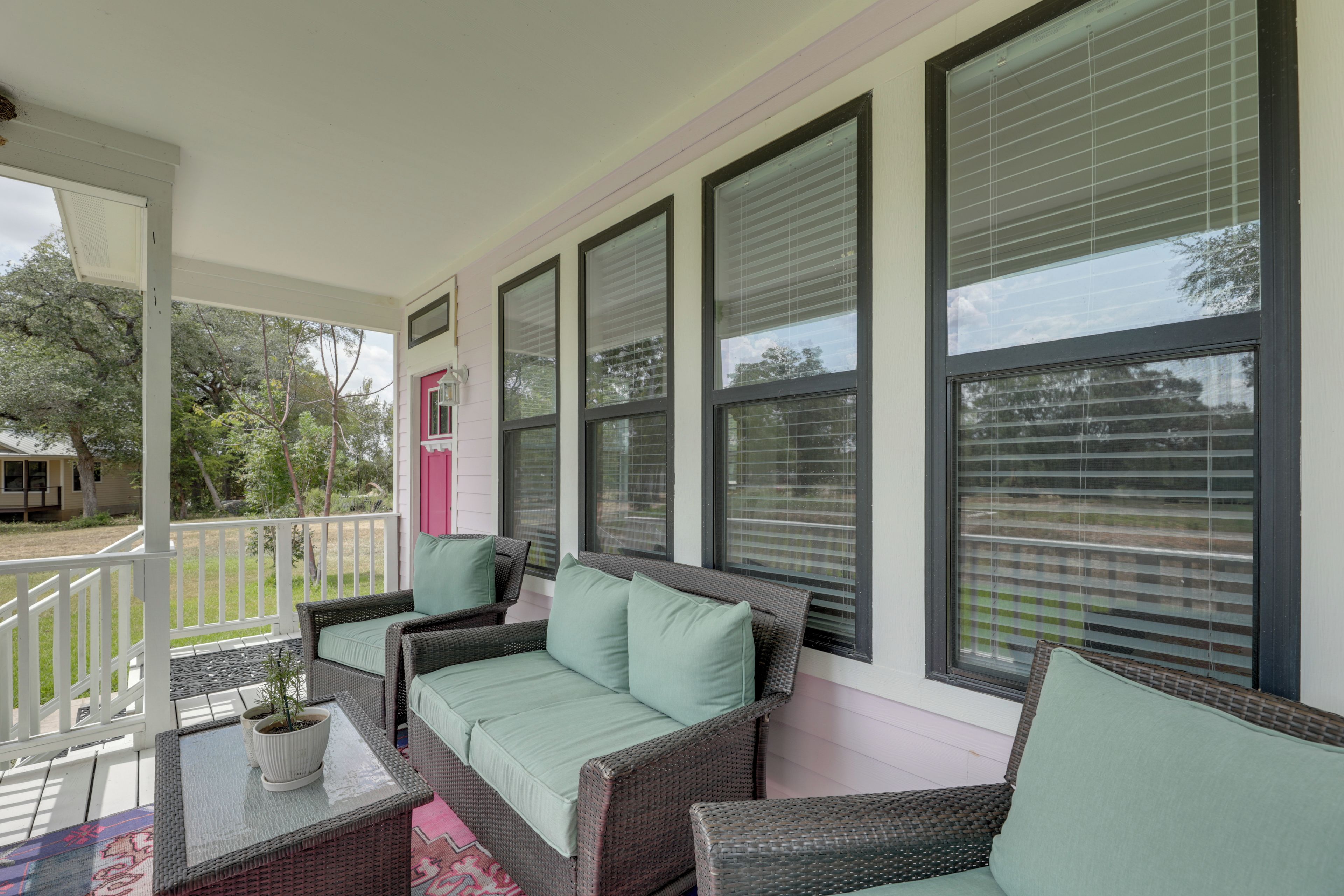 A covered porch with wicker furniture and a potted plant.