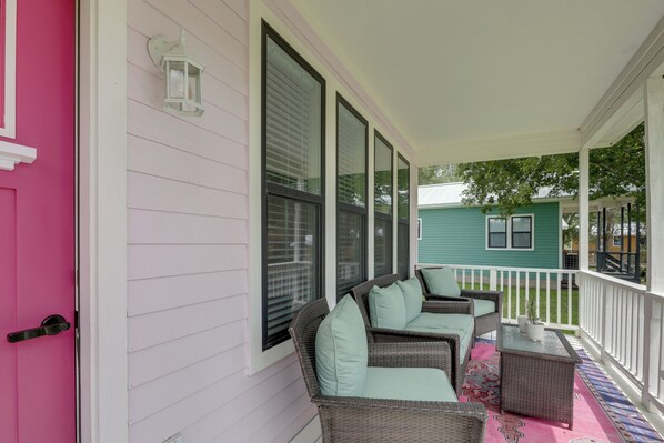 A porch with wicker furniture and a colorful rug.