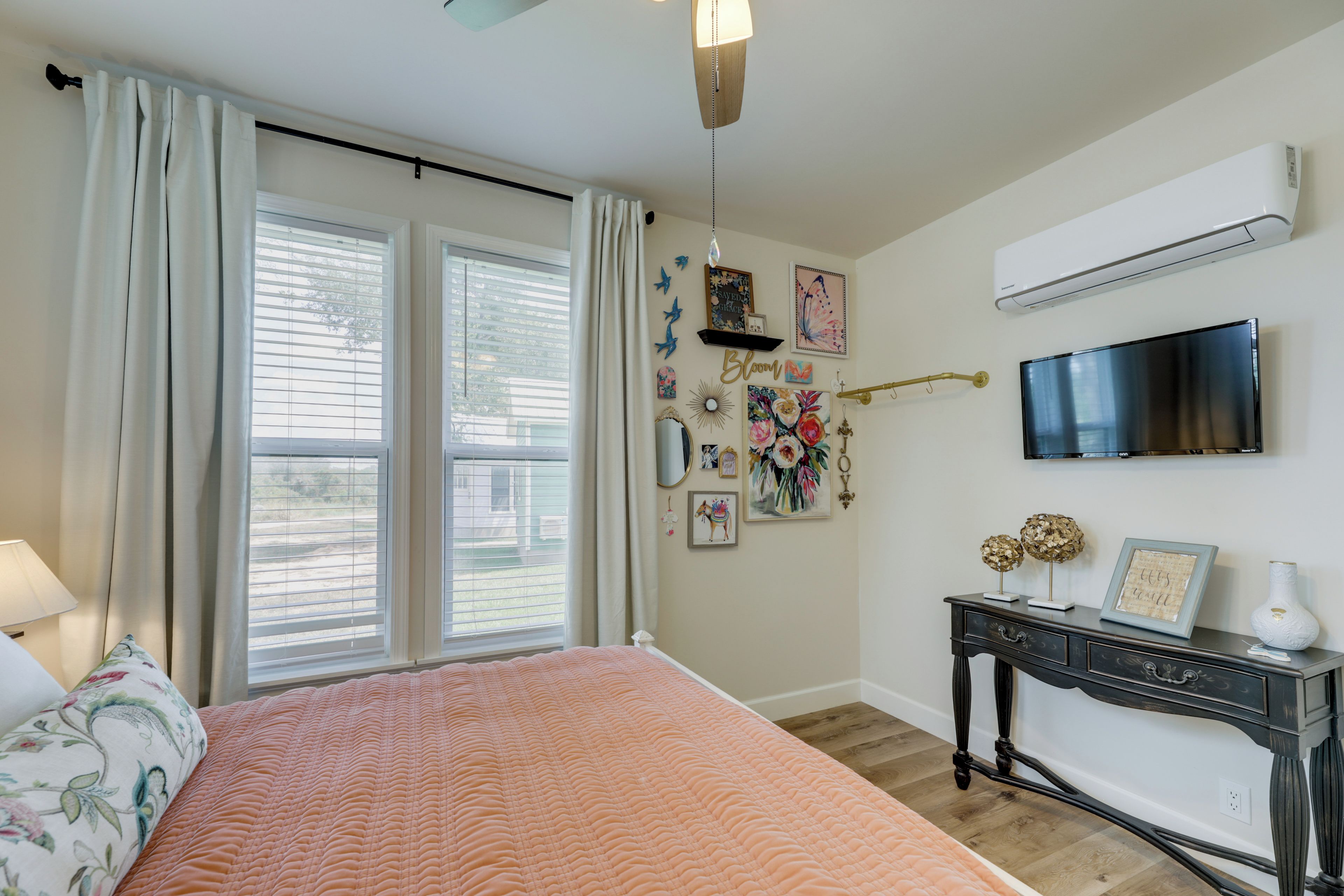 Ein Schlafzimmer mit einem Bett, einem Schminktisch, einem Fernseher und einem Fenster mit Vorhängen.