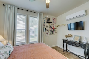 A bedroom with a bed, a dresser, a television, and a window with curtains.