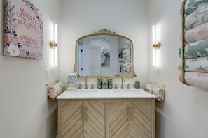 Un baño con tocador doble, un espejo grande y un mueble con estampado de espiga.