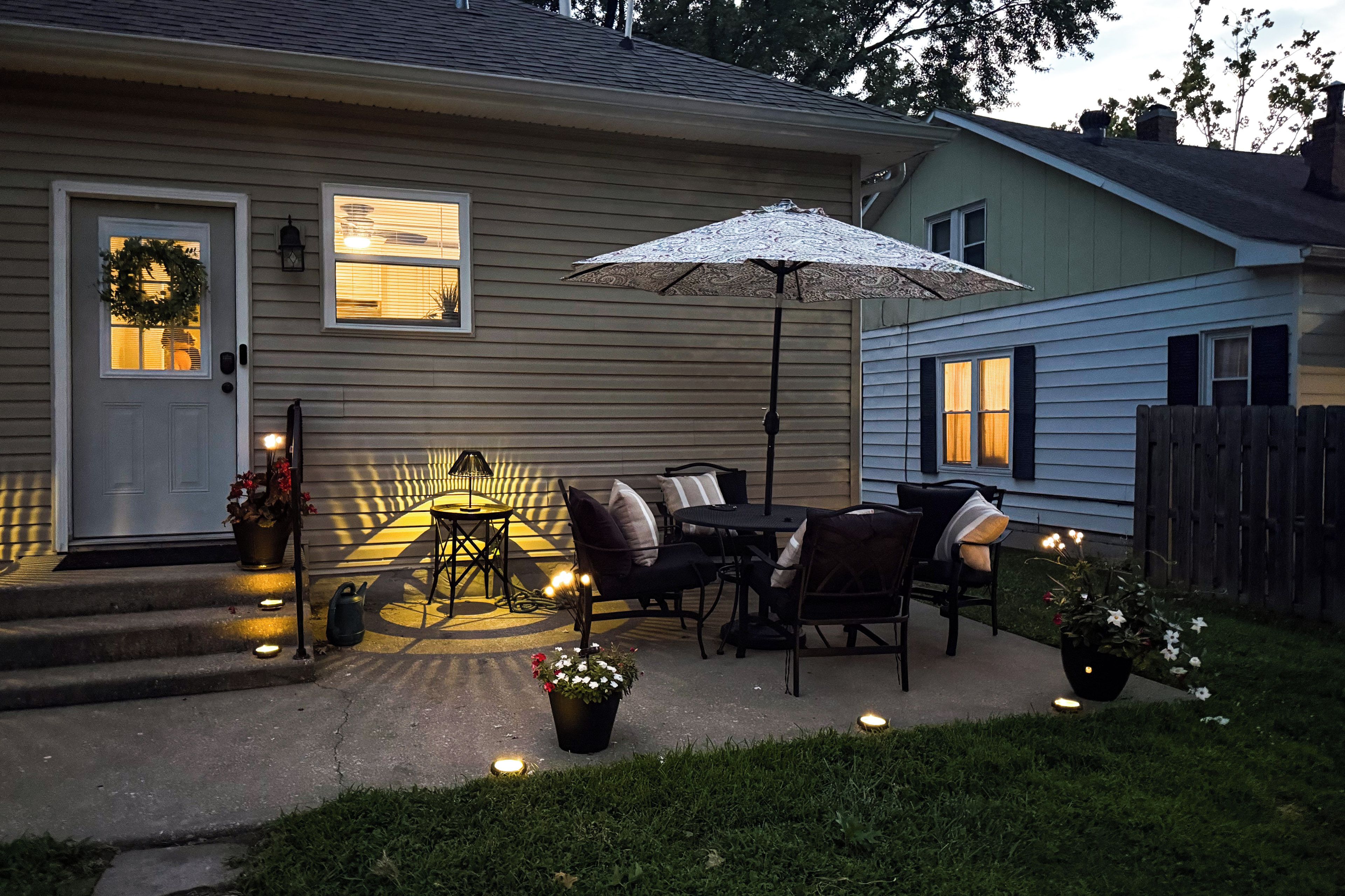 A residential house with a porch, outdoor seating, and a decorative umbrella.