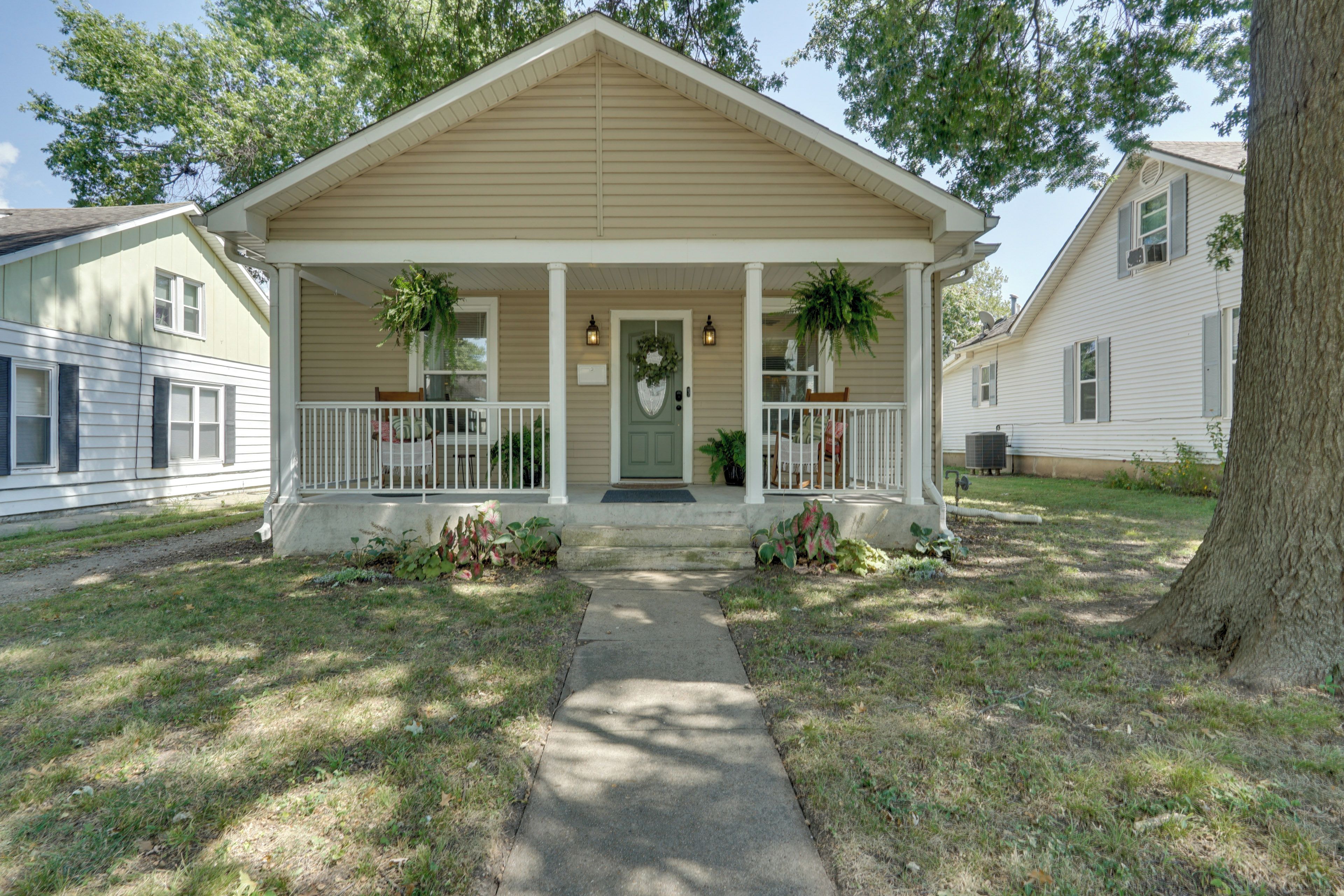 A two-story house with a front porch, a mailbox, and a small garden.