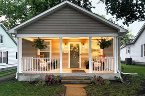 A two-story house with a covered porch, a front door, and a small front yard.