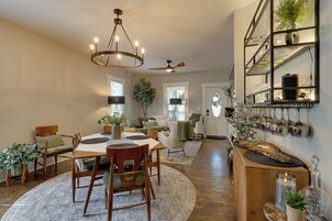 Amplia sala de estar con comedor, ventilador de techo y estante empotrado con objetos decorativos.