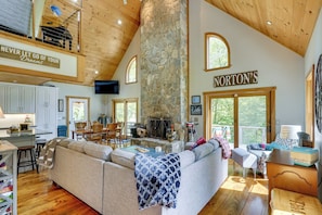 A spacious living area with a stone fireplace, a large couch, and a dining area with wooden furniture.