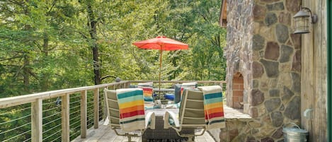 A wooden deck with outdoor furniture and a red umbrella.