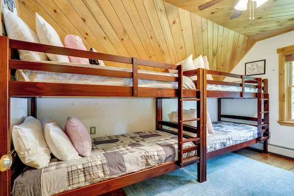 A bunk bed room with wooden walls and a sloped ceiling.