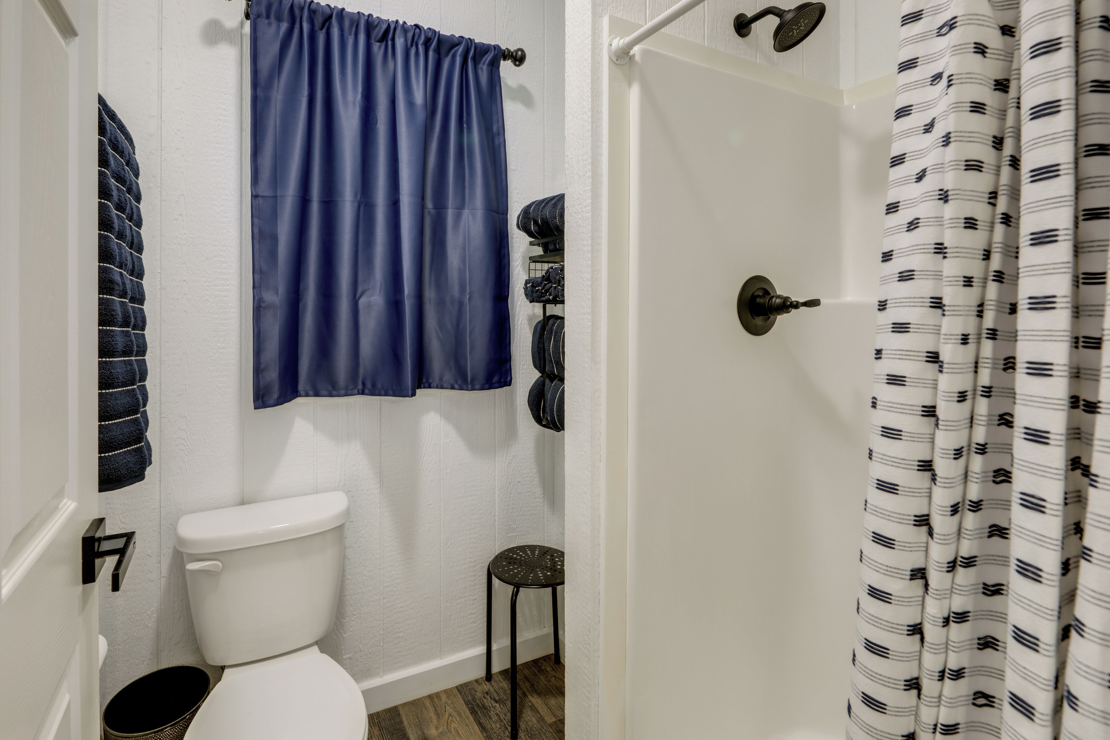 Une salle de bain avec des toilettes blanches, un rideau de douche bleu et un rideau à motifs.