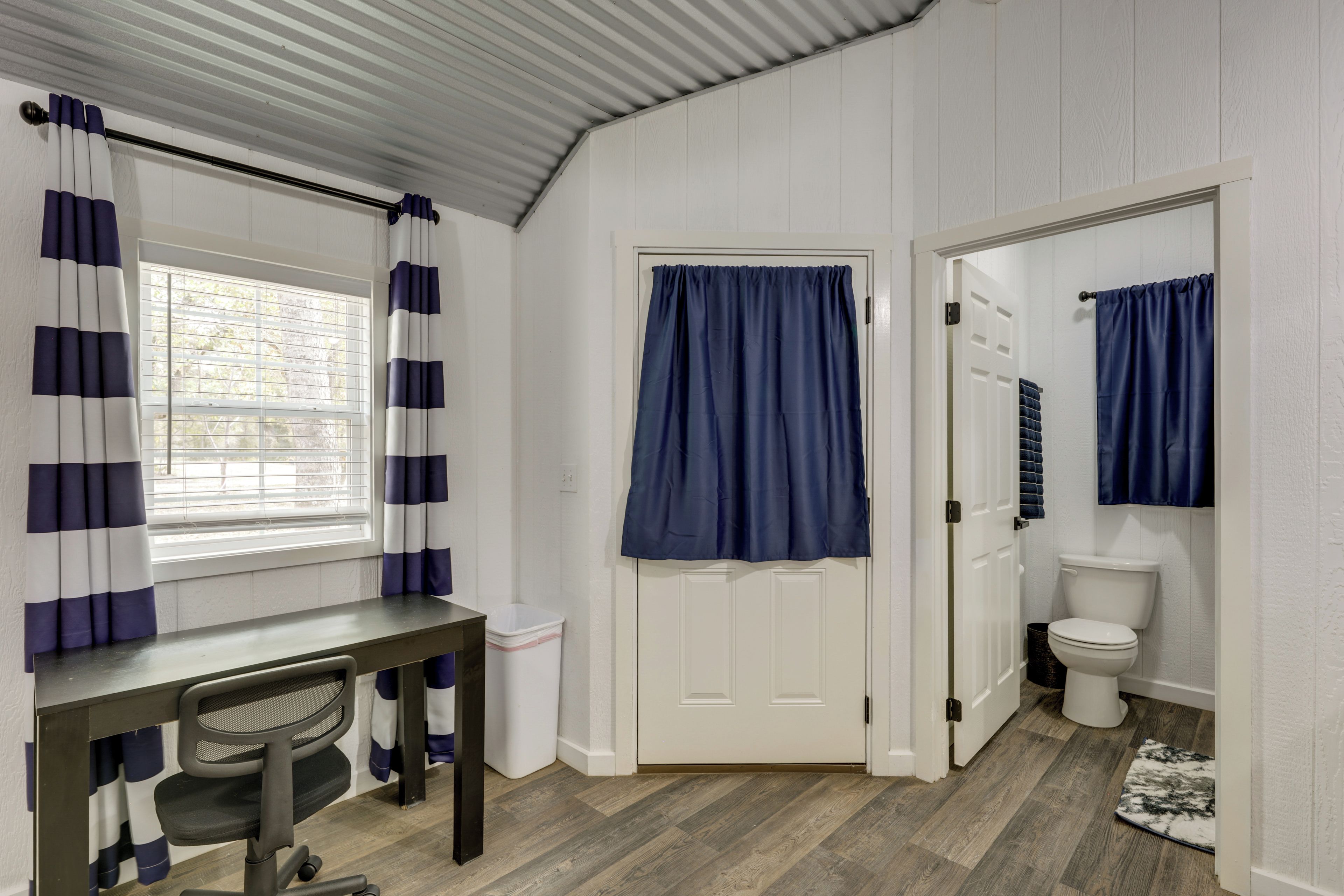 Une petite salle de bain comprenant des toilettes, un espace douche et une fenêtre avec des rideaux.