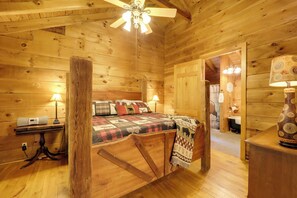 Quarto de cabana de madeira com uma cama, duas luminárias de cabeceira, uma mesa com uma luminária e um vaso decorativo.