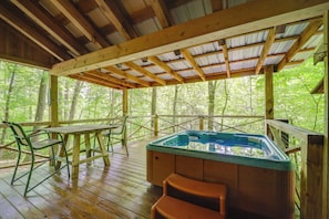 A wooden deck with a hot tub, wooden chairs, and a table. - Group of 6 Cabins on 92-acre Farm in Marion (Marion)