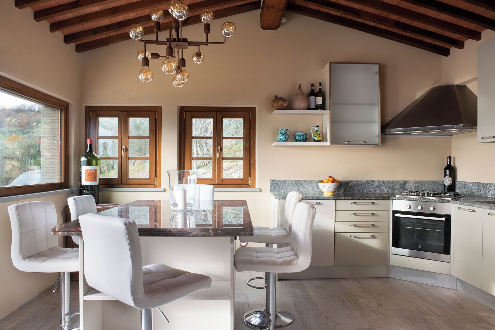 Una cucina moderna con zona pranzo, travi in legno a soffitto e vista sull'esterno.