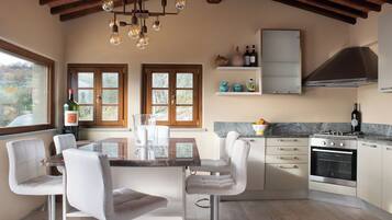 Una cucina moderna con zona pranzo, travi in legno a soffitto e vista sull'esterno.