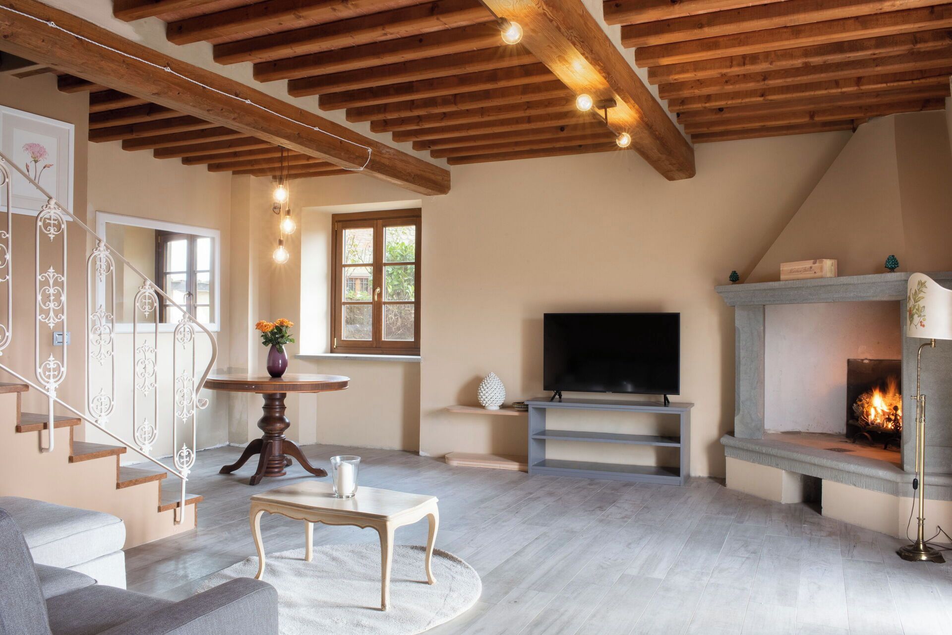 Un soggiorno con camino, televisione e una scala con ringhiere decorate.