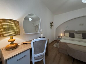 Ein Schlafzimmer mit Schreibtisch, Stuhl, Bett und einem großen Spiegel.