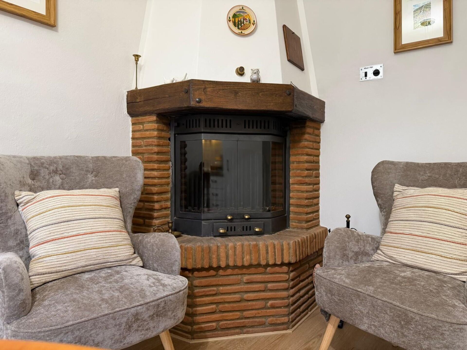 Una sala de estar con chimenea, dos sillones y un cuadro colgado en la pared.