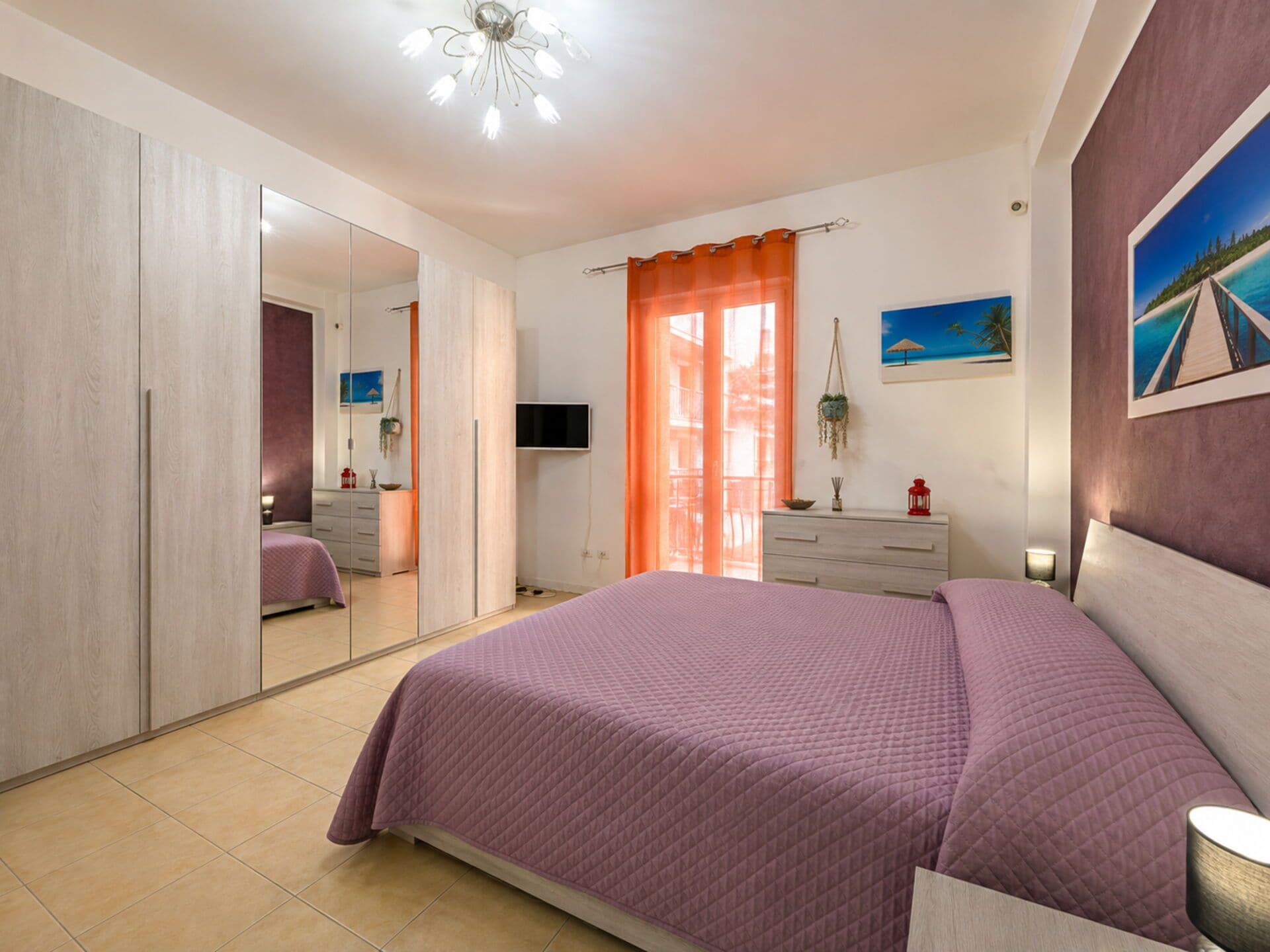 Un dormitorio con una cama grande, un armario, un televisor y un cuadro en la pared.