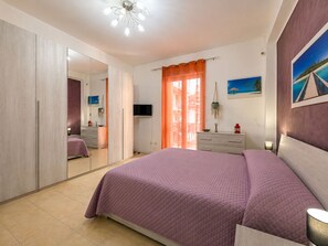 Quarto com uma cama grande, um guarda-roupa, uma televisão e um quadro na parede.