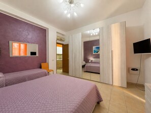 Ein Schlafzimmer mit zwei Betten, einem Spiegel, einem Fernseher und einem Kleiderschrank.