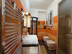 Ein modernes Badezimmer mit einer Glasdusche, einem weißen Waschbecken und einem Bidet.