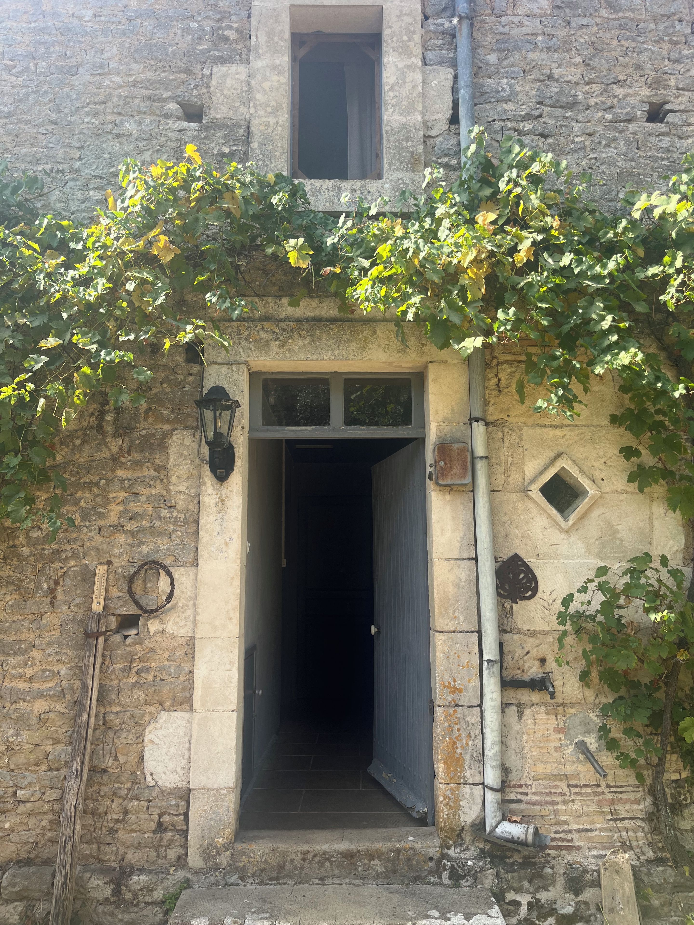 A stone building with a doorway, a small window above, and a wall-mounted light fixture.
