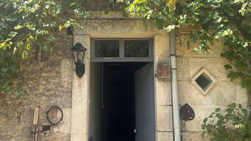 A stone building with a doorway, a small window above, and a wall-mounted light fixture.