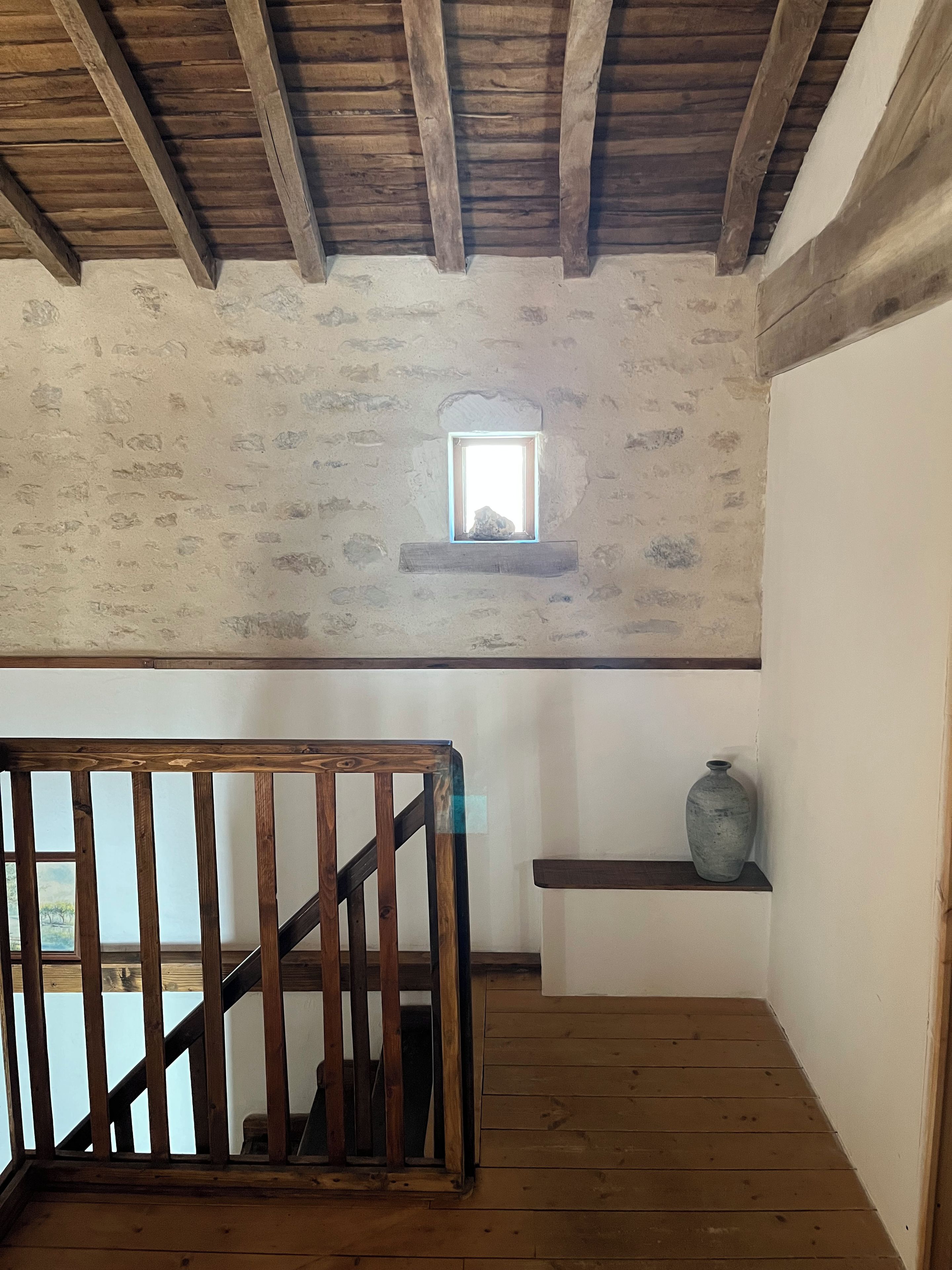Un escalier en bois, avec un plafond rustique et une petite fenêtre.
