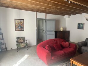 A living room with a red sofa, a wooden coffee table, a floral chair, and a cabinet. - Gite Chez Robin in the Deux-Sèvres (Ardin)